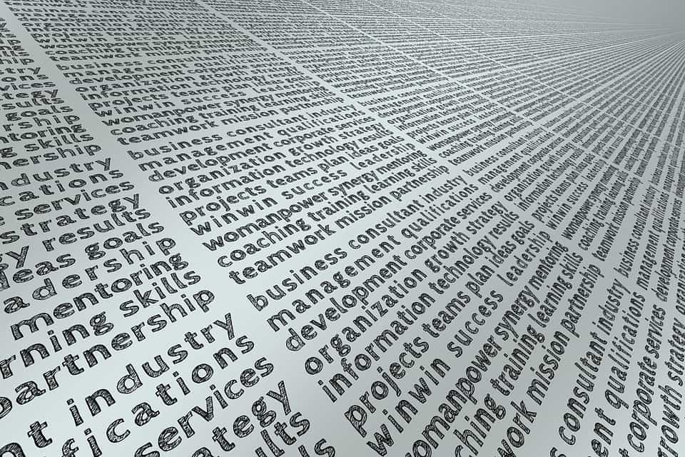 Repeating word cloud of business terms including teamwork, leadership, strategy, and management on a silver surface