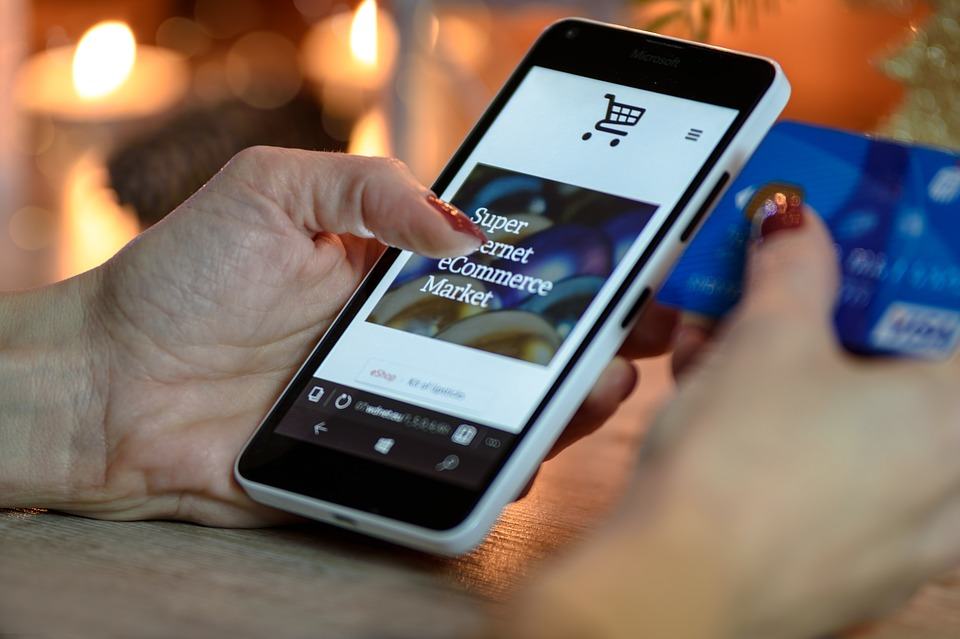 Woman holding a credit card and tapping an ecommerce store on a smartphone, illustrating mobile shopping security