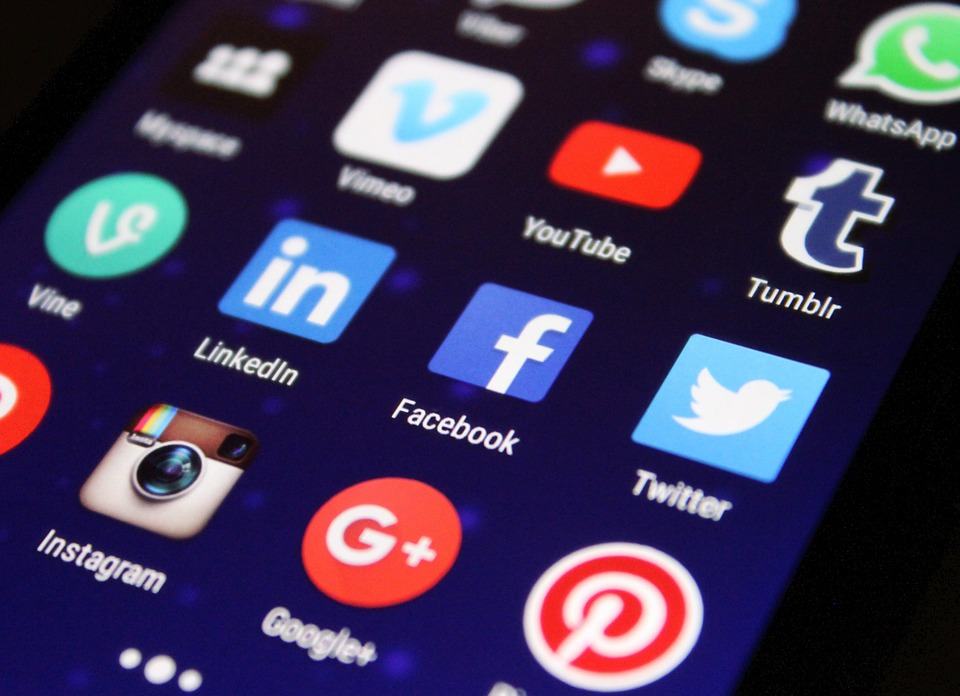 Smartphone screen showing a grid of social media app icons including Facebook, LinkedIn, Twitter, Instagram and YouTube