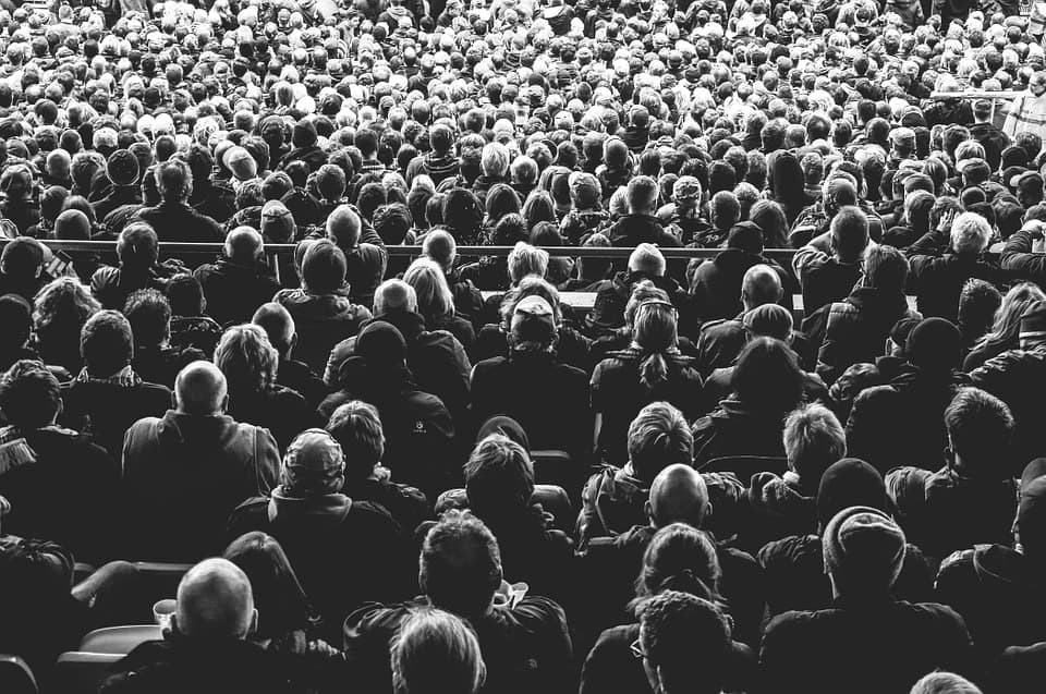 Large black-and-white crowd of people seated at an event, representing the broad audience reachable through guest posting