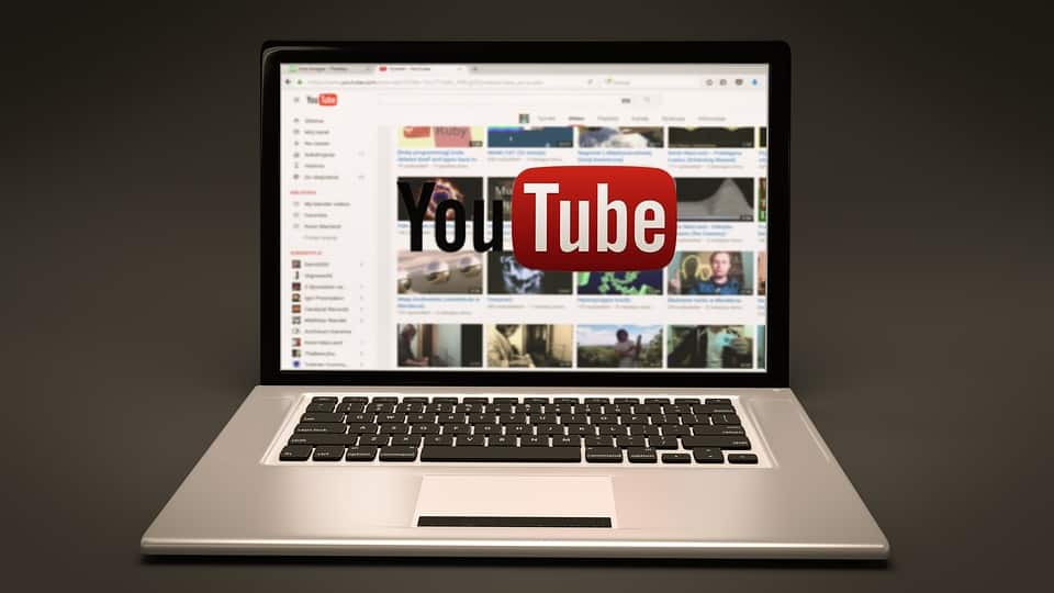 YouTube homepage displayed on a laptop screen with the YouTube logo overlaid