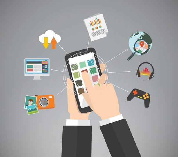 Flat design illustration of hands holding a smartphone with app icons surrounding it including cloud storage, analytics, camera and games