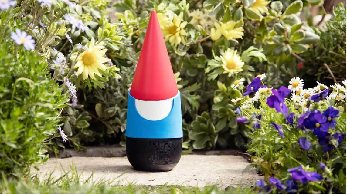 Google Home smart speaker disguised as a garden gnome with a red hat placed among flowers outdoors