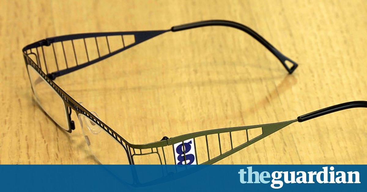 The Guardian branded eyeglasses with lattice-style metal frames resting on a wooden surface