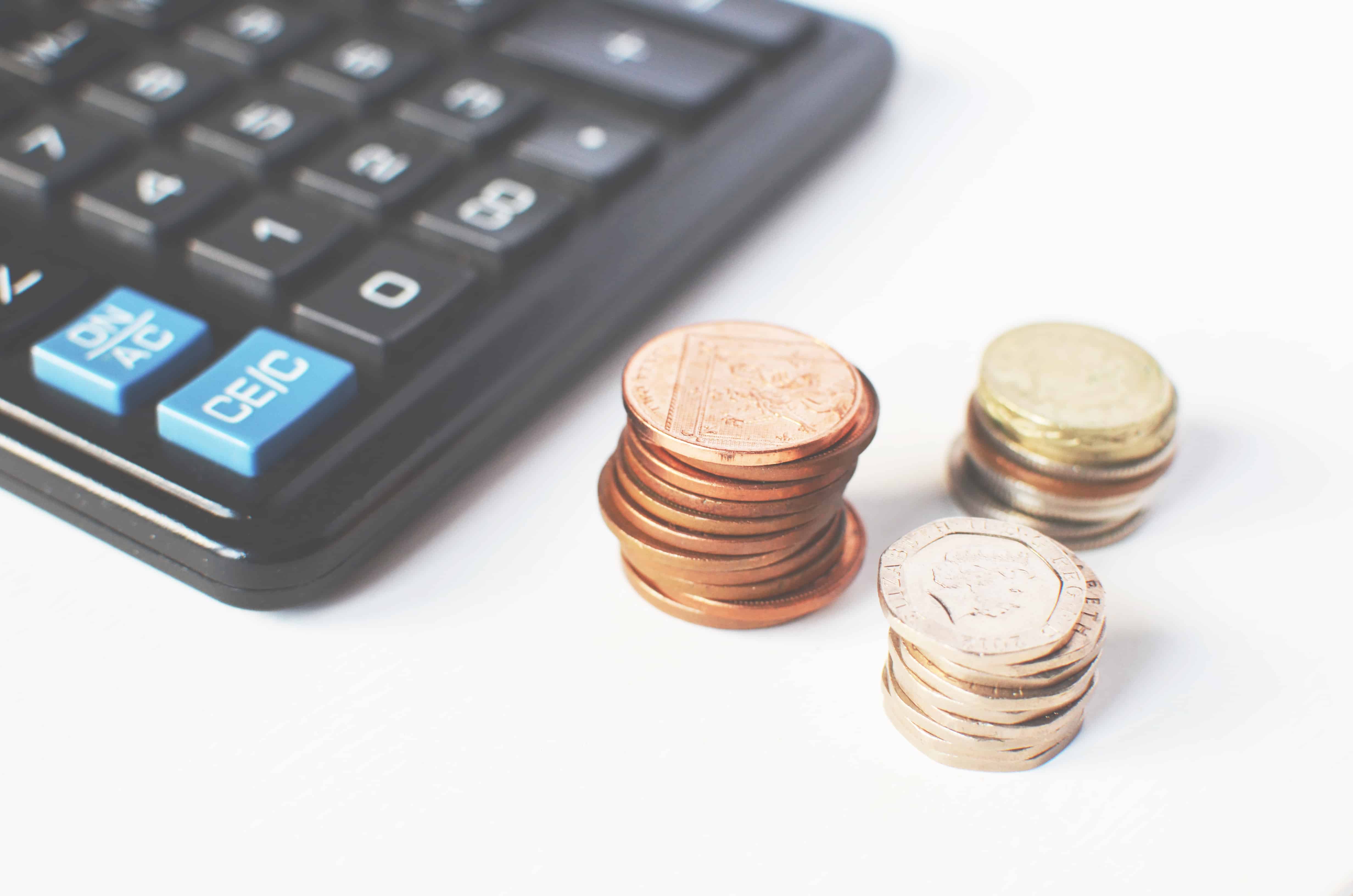 Stacks of copper and silver coins next to a calculator representing ROI and marketing budget calculations