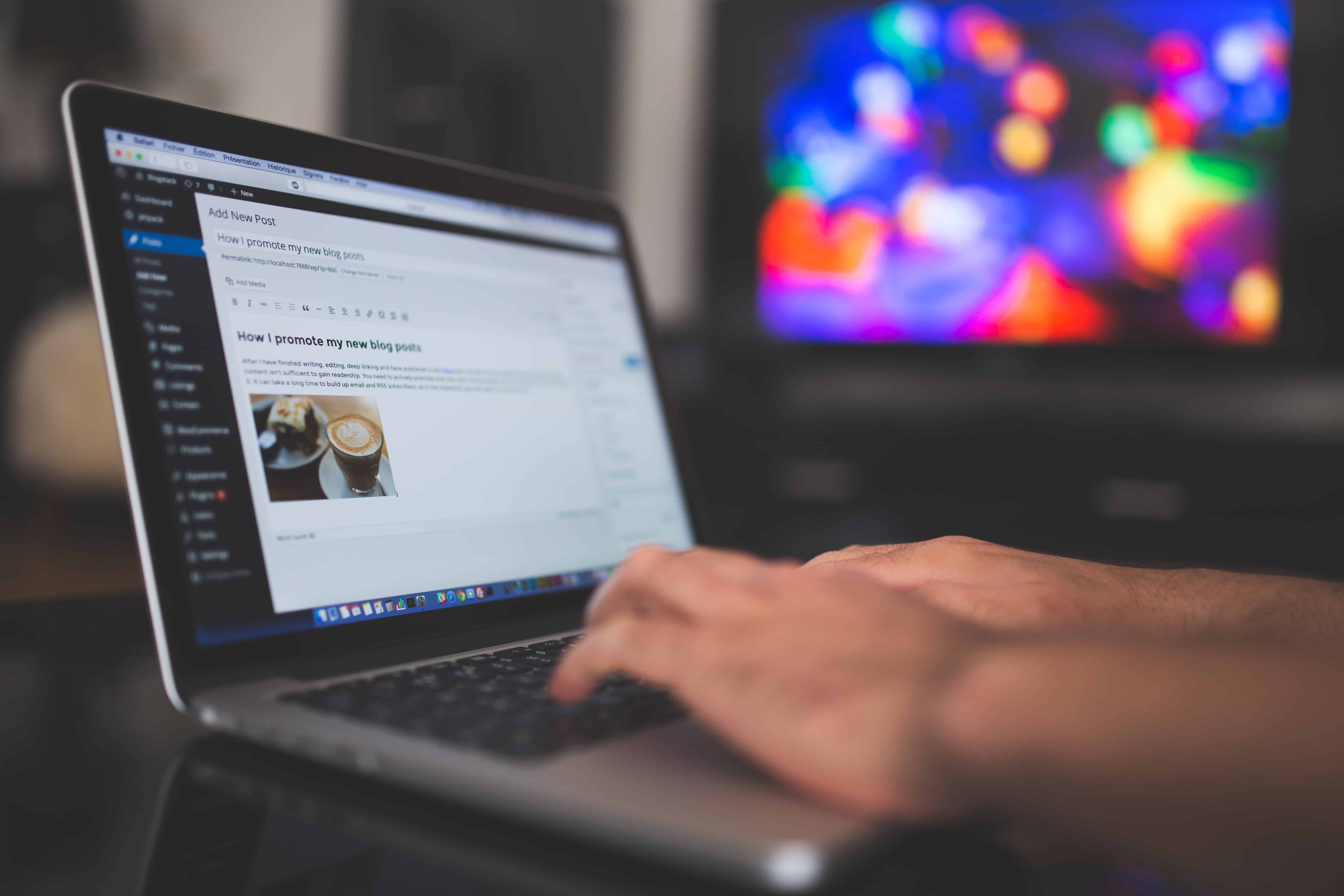 Hand typing on a MacBook showing a WordPress Add New Post editor screen