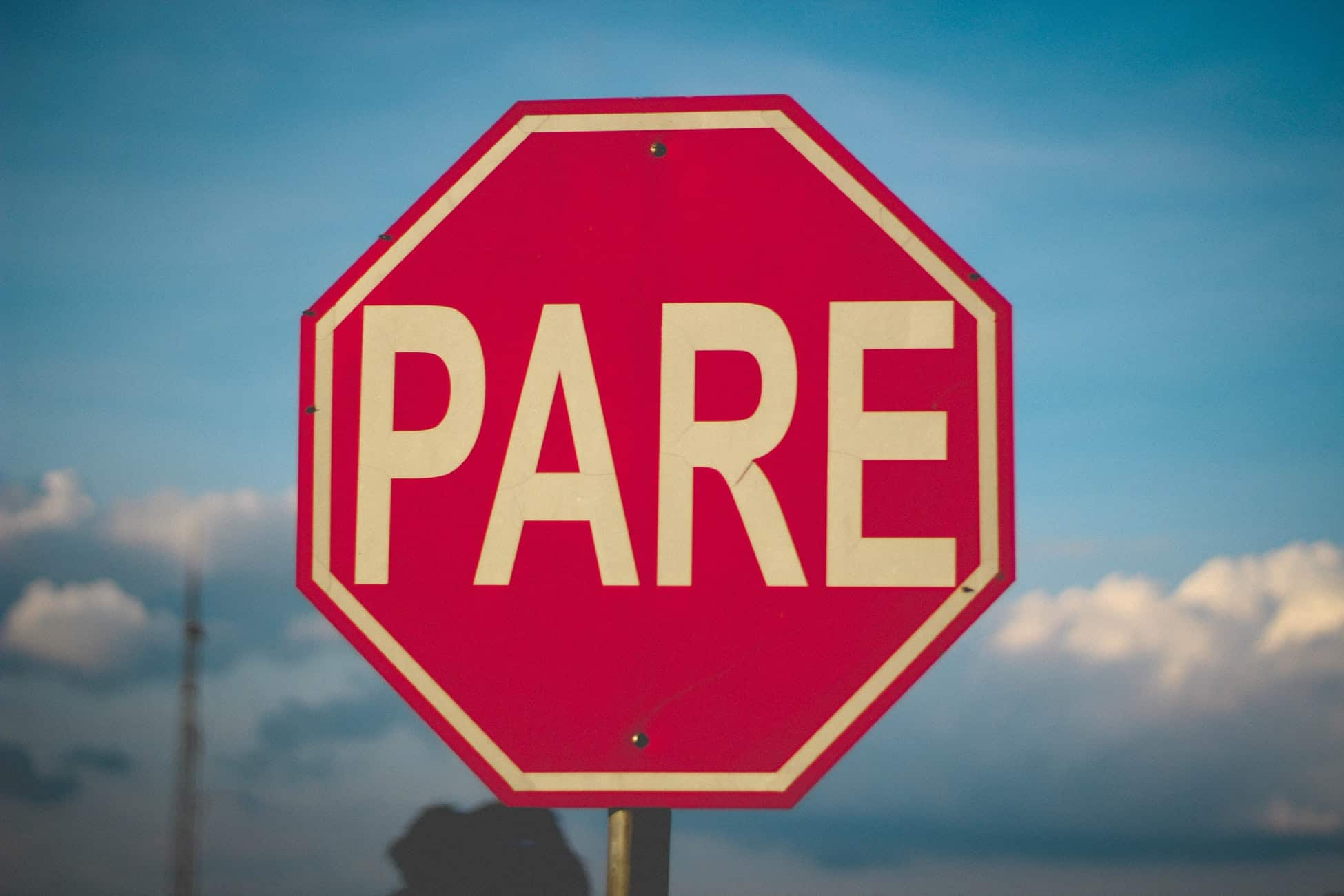 Red octagonal Pare stop sign against a blue sky, symbolising risks when outsourcing online services